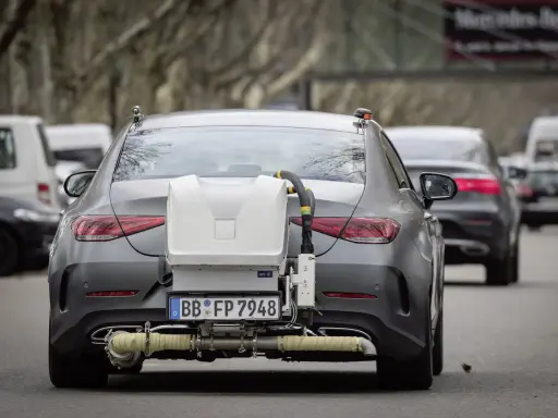 Coche gris con equipo de medición de emisiones euro 6 en la parte trasera, en pruebas de carretera.