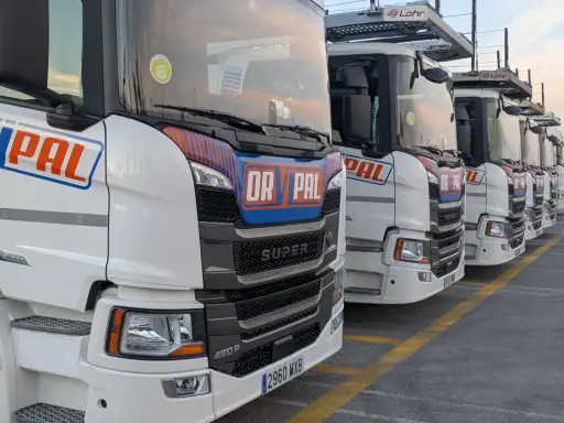 Fila de camiones Scania Super blancos, listos para la carretera.
