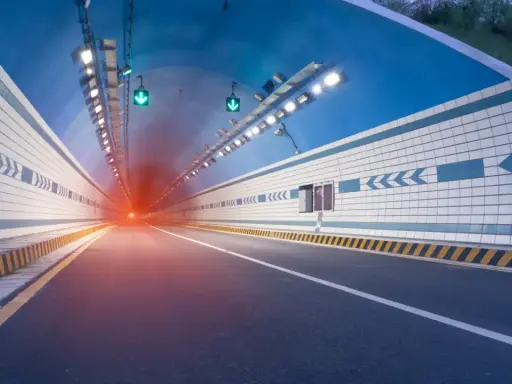 El efecto túnel se percibe al entrar en este túnel vial iluminado, con luces verdes y un resplandor rojo al fondo.
