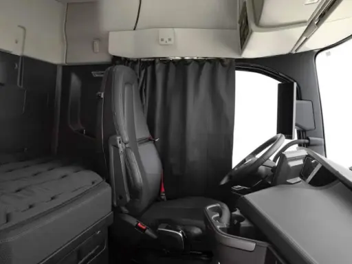 Interior de un camión Volvo FH XXL. Asiento del conductor, cama y volante.