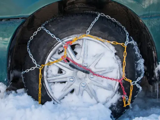 Neumático con cadenas de nieve instaladas, mostrando cómo se ponen las cadenas de nieve para circular en condiciones invernales.