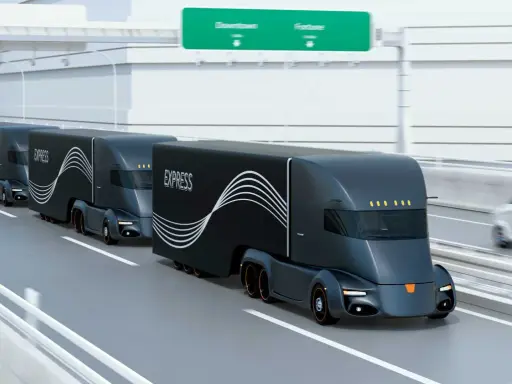 Tren de camiones del futuro, negros y aerodinámicos, circulando por una autopista.