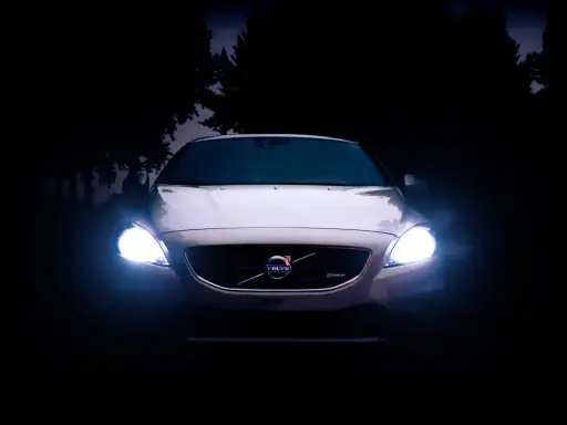 Volvo blanco con luces encendidas en la oscuridad.