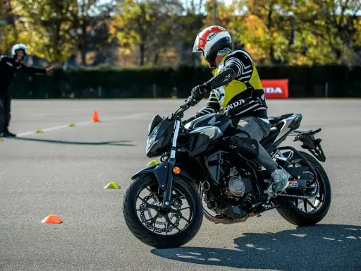 Motociclista con equipo de protección en una pista de examen con conos.
