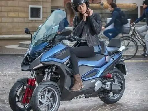 Mujer ajustándose el casco en una moto de 3 ruedas azul, ideal para conducir con carnet B.