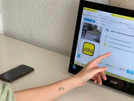 Persona estudiando para el examen de moto A2. La pantalla muestra una pregunta sobre la prueba de alcoholemia, indicando que el examen tiene 38 preguntas.