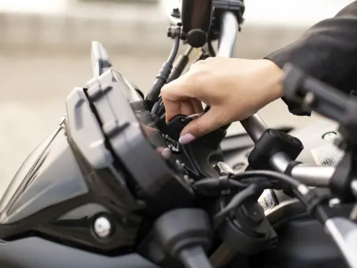 Mano insertando la llave de contacto en una moto, preparándose para el carnet A2.