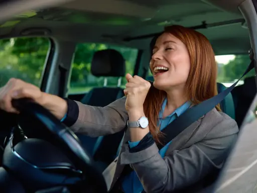 Mujer sonríe y canta al volante, feliz de conducir en España con su carnet de conducir ucraniano.
