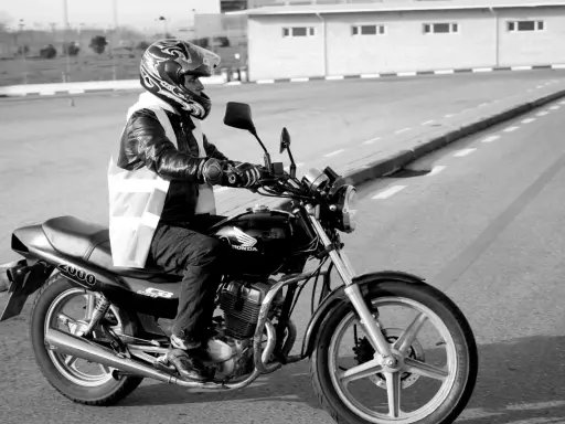 Motociclista con casco y chaleco reflectante en una Honda, preparándose para obtener el carnet de moto grande.
