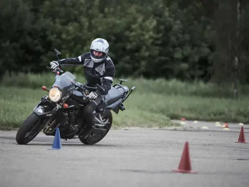 Persona con casco y equipación de moto practica maniobras en circuito con conos. Averigua el carnet de moto a1 precio.