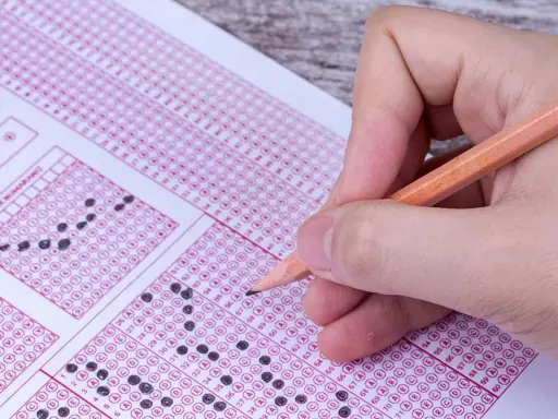Mano con lápiz completando un examen de respuestas múltiples. ¿Cuántas preguntas son el examen de conducir?
