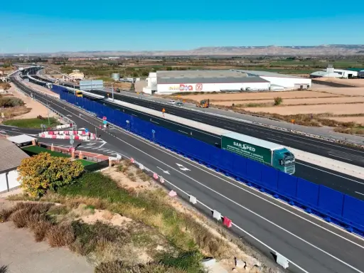 Camión de SAR SPED circula por la a68 autovía, con barreras acústicas azules y paisaje rural al fondo.