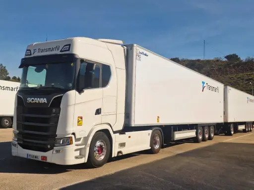 Un mega camión blanco Scania con dos remolques largos de Transmarfil, listo para transportar mercancías.