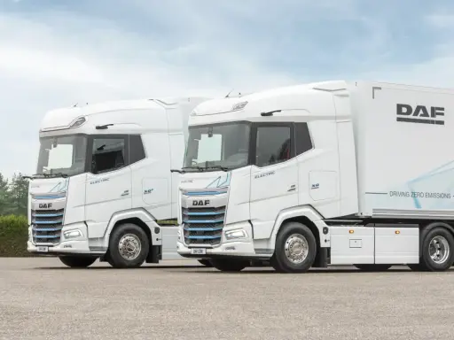 Dos camiones DAF XG Plus eléctricos, blancos, con el interior visible. Uno lleva un remolque DAF.