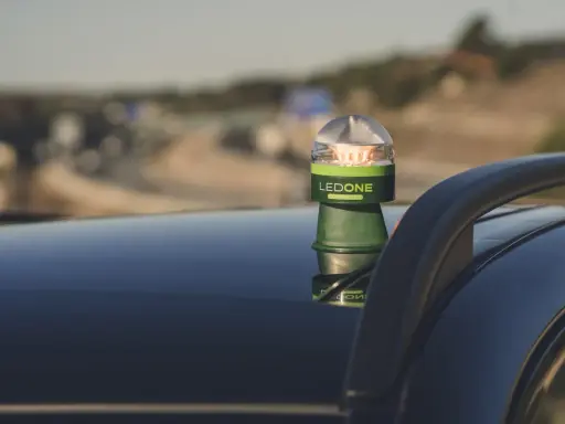 Baliza LED verde y plateada, modelo LEDONE CONNECTED, sobre el techo de un coche. Es una preseñalización de peligro para advertir en carretera.
