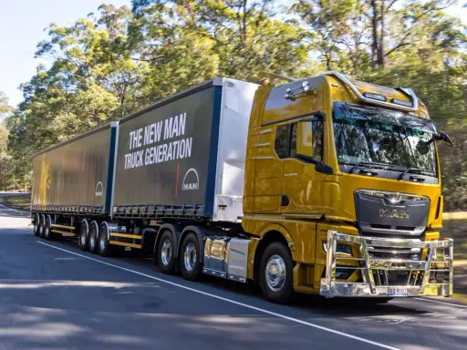 Camión amarillo brillante de MAN en carretera, con el lema "The New MAN Truck Generation". Ideal para mostrar que pueden circular los camiones los domingos.