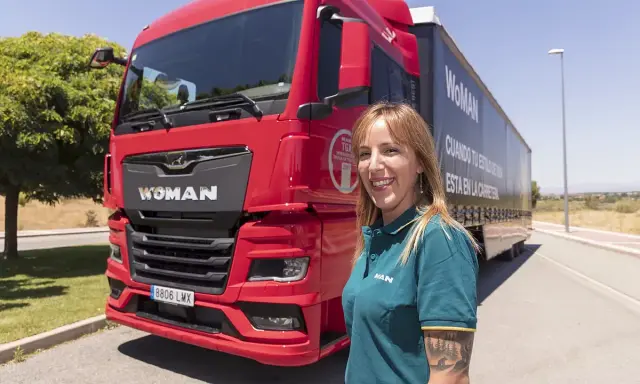 Mujer sonriente junto a un camión rojo MAN TGX. Averigua cuanto cuesta el carnet C+E para conducir este vehículo.