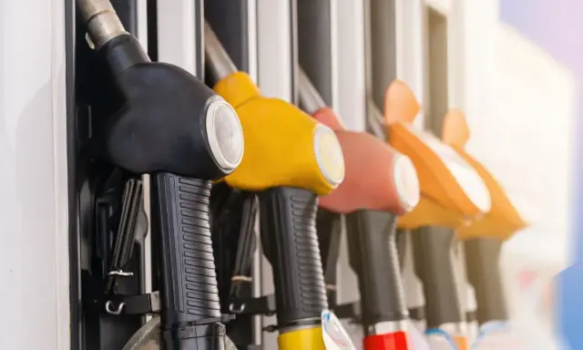 Mangueras de gasolinera en fila, listas para llenar el tanque y promover el ahorro de combustible.