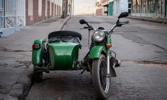 Motocicleta verde con sidecar, lista para recorrer calles empedradas. Un clásico que aún recibe permiso a motocicletas con sidecar.