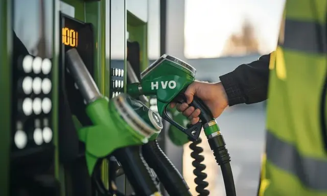 Mano con boquilla HVO verde, lista para la declaración de gasóleo profesional. El surtidor muestra 100.
