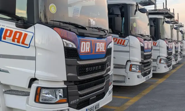 Fila de camiones Scania Super blancos, listos para la carretera.