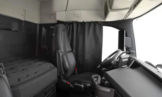 Interior de un camión Volvo FH XXL. Asiento del conductor, cama y volante.