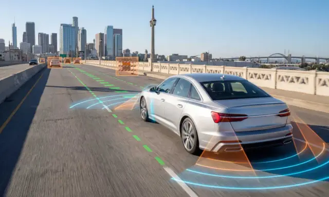 Un coche plateado en una autopista urbana, con gráficos que muestran sus **sistemas de ayuda a la conducción** detectando otros vehículos y obstáculos.