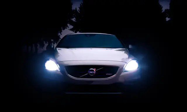Volvo blanco con luces encendidas en la oscuridad.