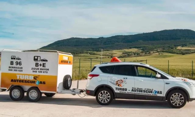 Coche blanco de autoescuela Turbo con remolque. Preparados para obtener el carnet B+E.