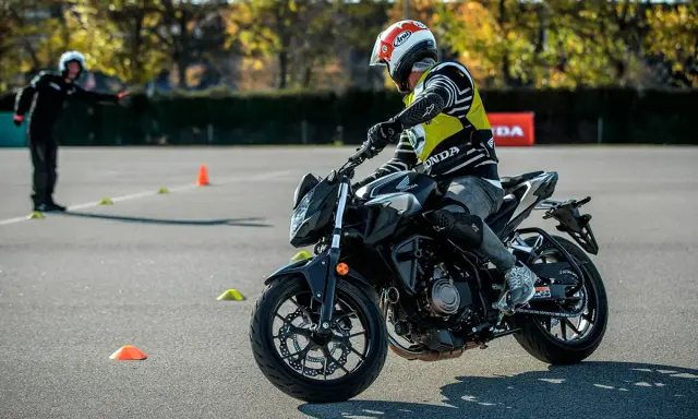 Motociclista con equipo de protección en una pista de examen con conos.
