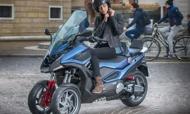 Mujer ajustándose el casco en una moto de 3 ruedas azul, ideal para conducir con carnet B.