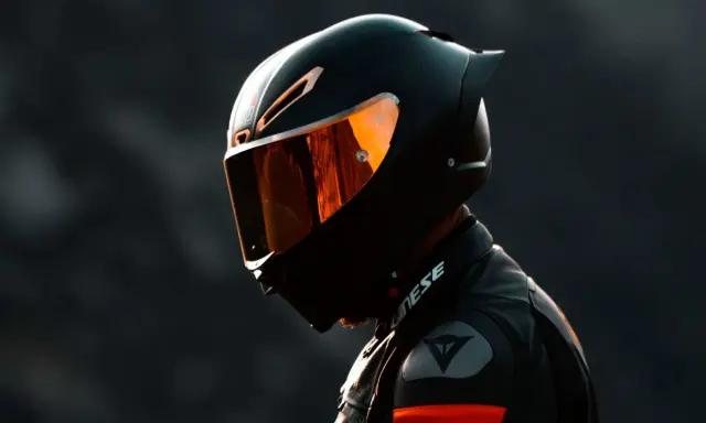 Motociclista con casco negro y visor naranja, listo para la acción. El uso obligatorio de casco es clave para la seguridad.