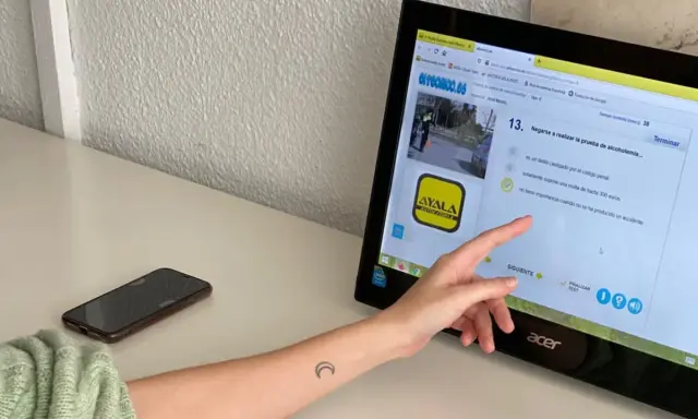 Persona estudiando para el examen de moto A2. La pantalla muestra una pregunta sobre la prueba de alcoholemia, indicando que el examen tiene 38 preguntas.