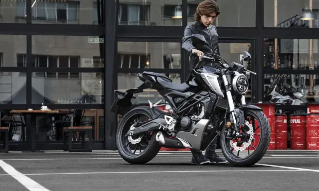Joven con chaqueta de cuero junto a una moto negra, listo para obtener su a1 permiso de conducir.