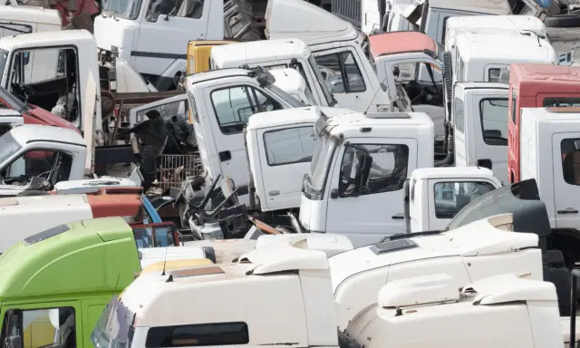 Desguace de camiones. Se aprecian cabinas blancas y verdes, algunas con partes oxidadas, listas para cumplir los requisitos de achatarramiento de camiones.
