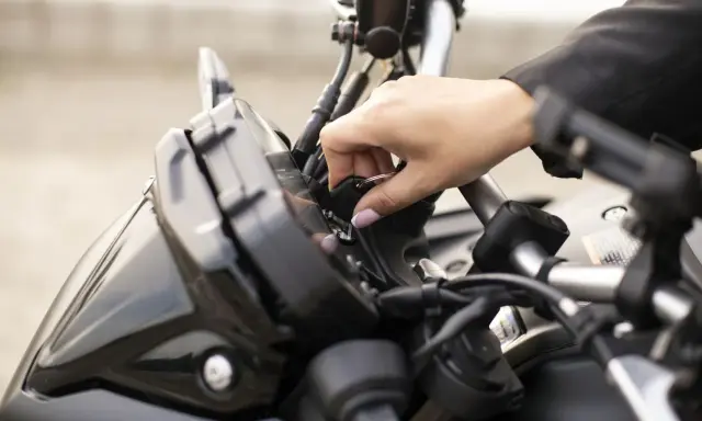 Mano insertando la llave de contacto en una moto, preparándose para el carnet A2.