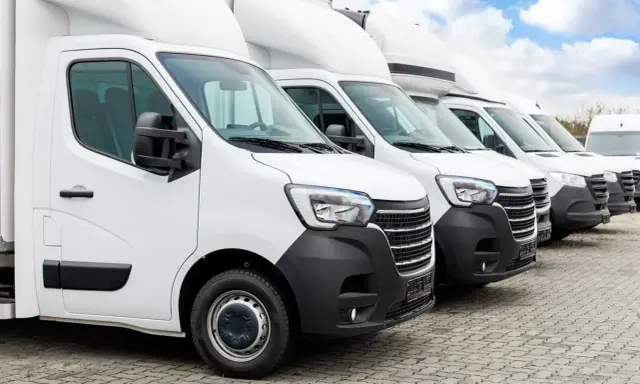 Fila de furgonetas blancas listas para la entrega. El modelo dgt n1 es el primero de la fila, con un diseño moderno y robusto.