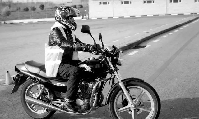 Motociclista con casco y chaleco reflectante en una Honda, preparándose para obtener el carnet de moto grande.