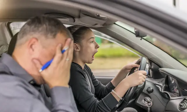 Instructor desesperado mientras una joven conductora, con cara de sorpresa, intenta sacarse el carnet de coche.