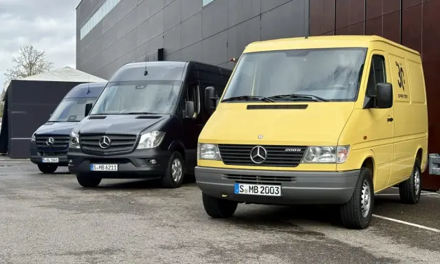 Tres furgonetas Mercedes-Benz Sprinter, una amarilla conmemorativa de 30 años, una negra y una azul, aparcadas frente a un edificio moderno.
