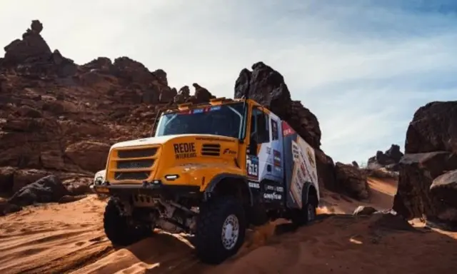 Camión Iveco Dakar amarillo compitiendo en un terreno desértico rocoso y arenoso, levantando polvo.
