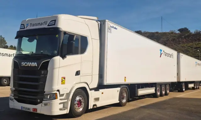 Un mega camión blanco Scania con dos remolques largos de Transmarfil, listo para transportar mercancías.