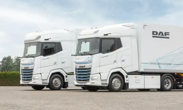 Dos camiones DAF XG Plus eléctricos, blancos, con el interior visible. Uno lleva un remolque DAF.