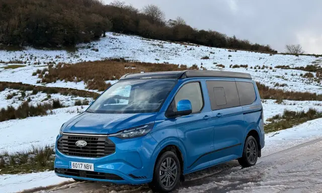 Furgoneta phev azul aparcada en un camino nevado, lista para una aventura invernal.