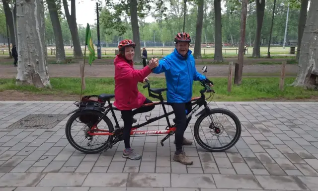 Pareja feliz en un eje tandem triaxial, disfrutando de un paseo en bicicleta por el parque.