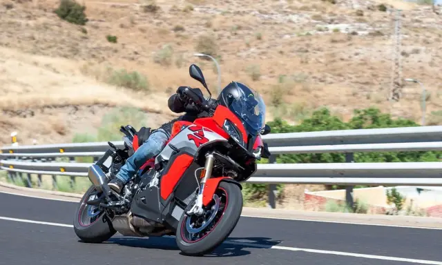 Motociclista en moto deportiva roja y gris en carretera. ¿Cuánto se tarda en sacar el carnet de moto?