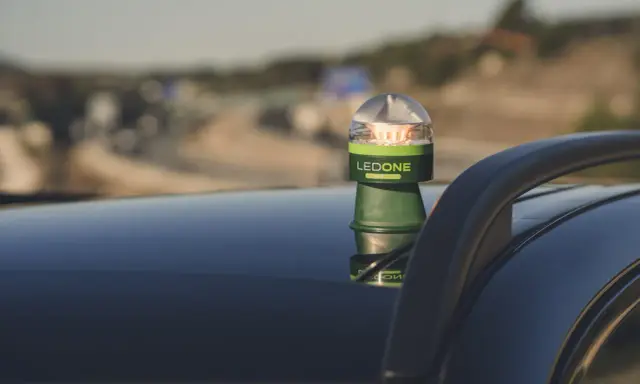 Baliza LED verde y plateada, modelo LEDONE CONNECTED, sobre el techo de un coche. Es una preseñalización de peligro para advertir en carretera.