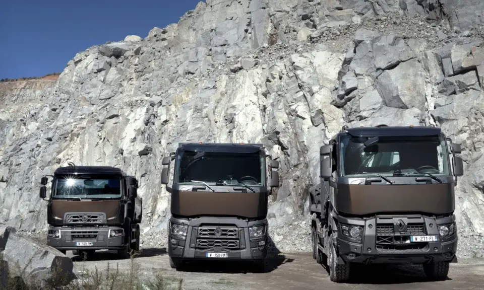 Tres robustos renault trucks modelos posan ante un imponente acantilado de cantera, listos para el trabajo pesado.
