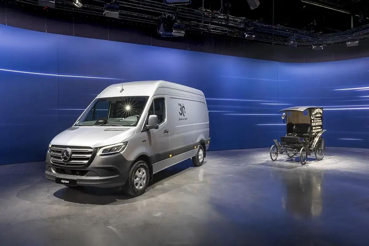 Un moderno sprinter plateado junto a un antiguo carruaje, celebrando 30 años de evolución en el transporte.
