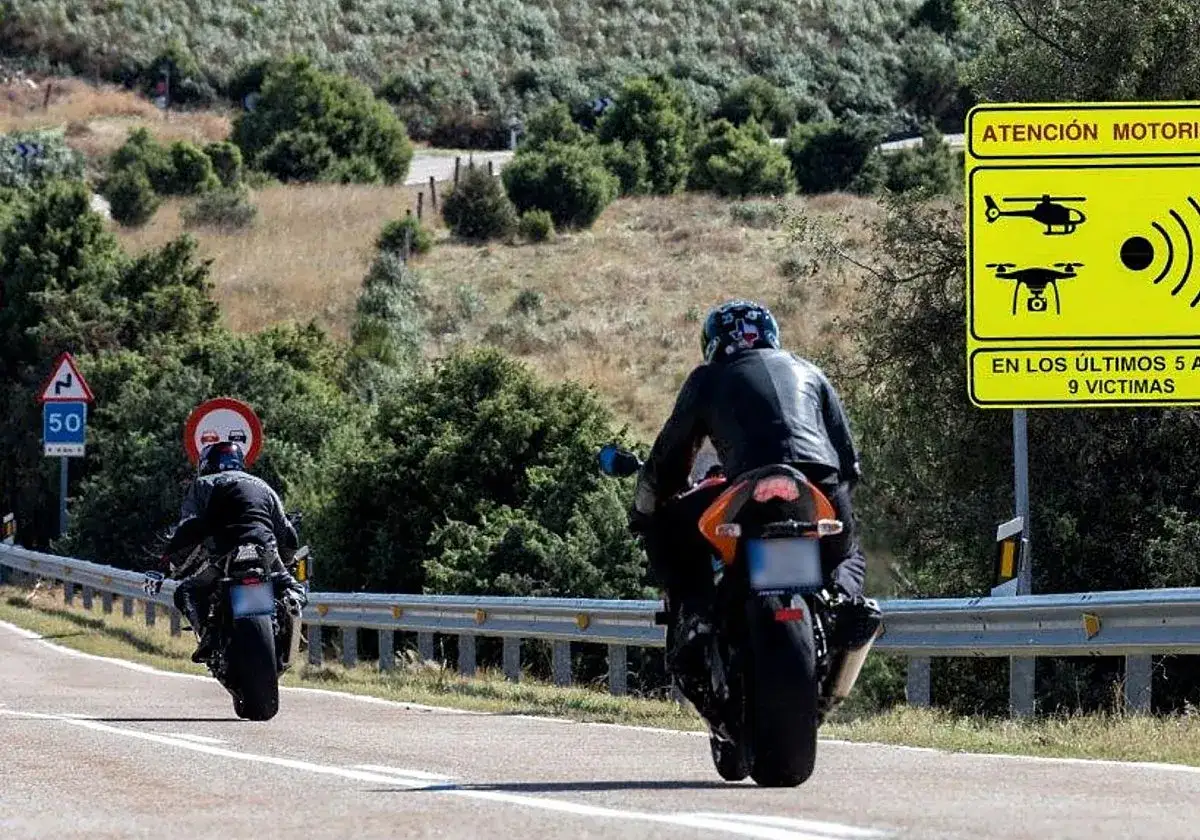 Dos motociclistas circulan por una carretera rural. Una señal advierte que una motocicleta puede circular por el arcén.